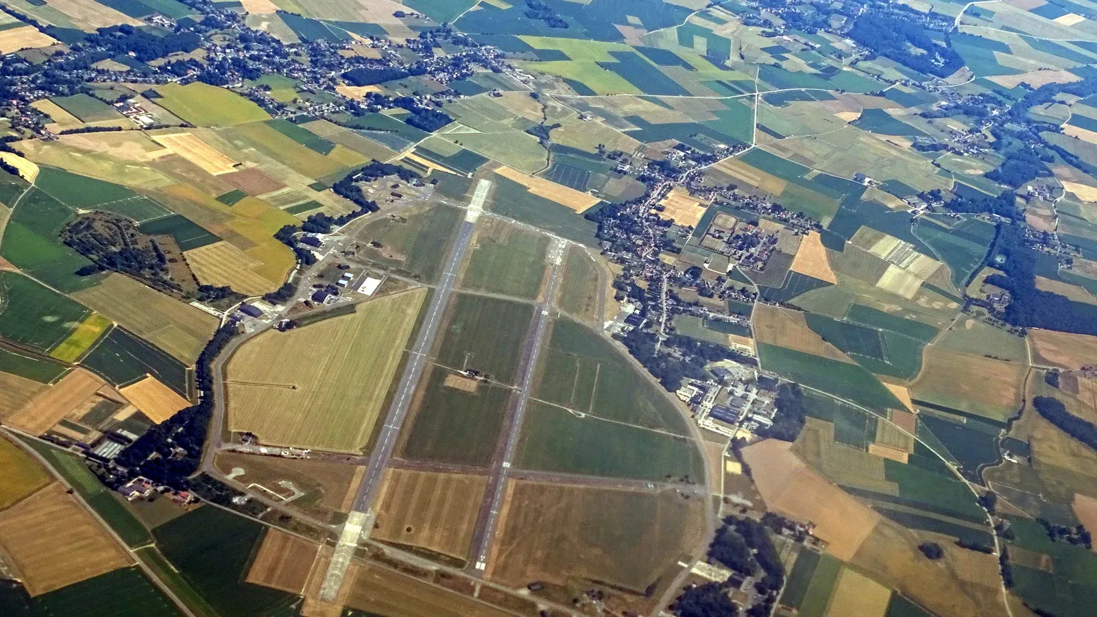 Vue aérienne de la base aérienne de Beauvechain, avec ses deux pistes parallèles entourées de champs et de villages