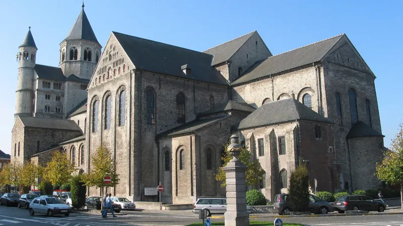 La collégiale Sainte-Gertrude de Nivelles sous un ciel bleu, avec des arbres aux feuilles d'automne