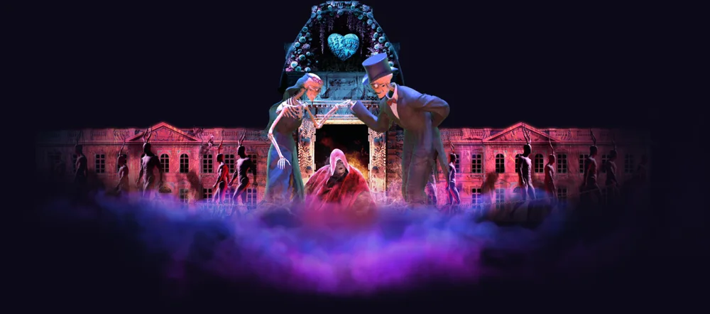 Projection monumentale sur la façade du château d'Hélécine : un couple de personnages squelettiques en tenue de soirée, dans la brume violette