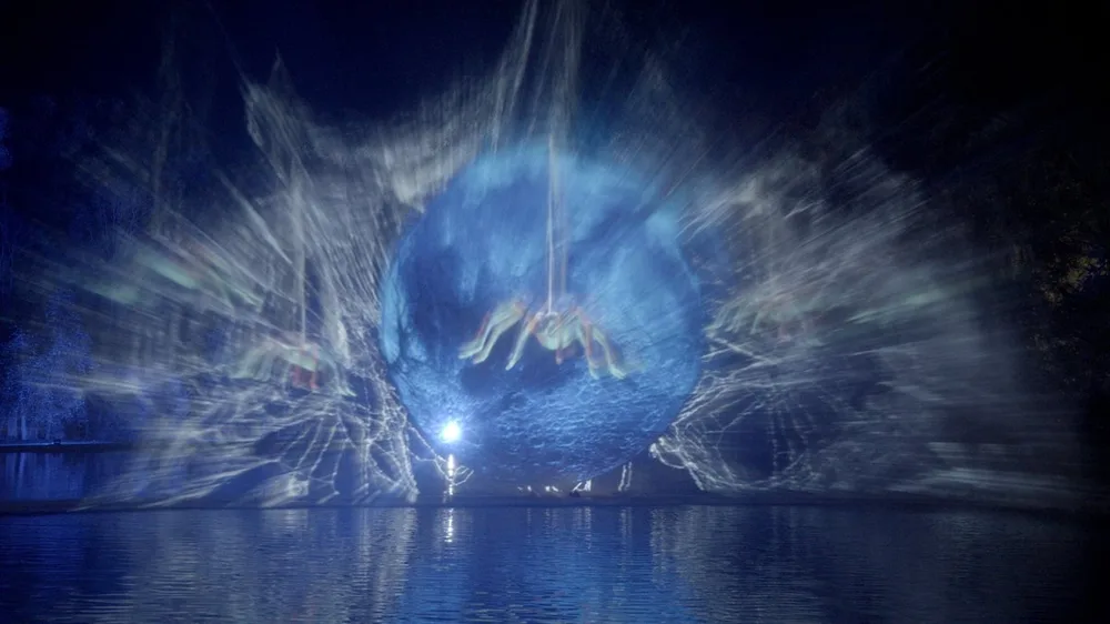 Projection d'une sphère lumineuse sur un écran d'eau, au-dessus du lac du domaine d'Hélécine, de nuit