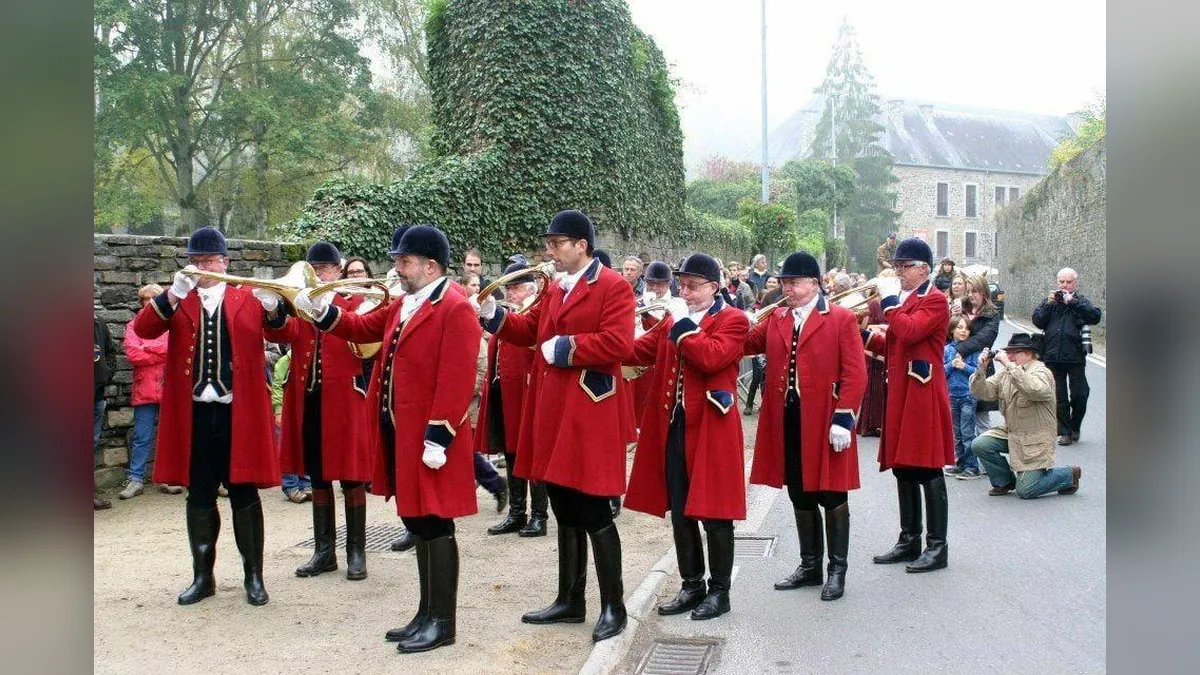 Sonneurs de trompe de chasse en veste rouge jouant dans une rue de Villers-la-Ville lors d'une fête de la Saint-Hubert