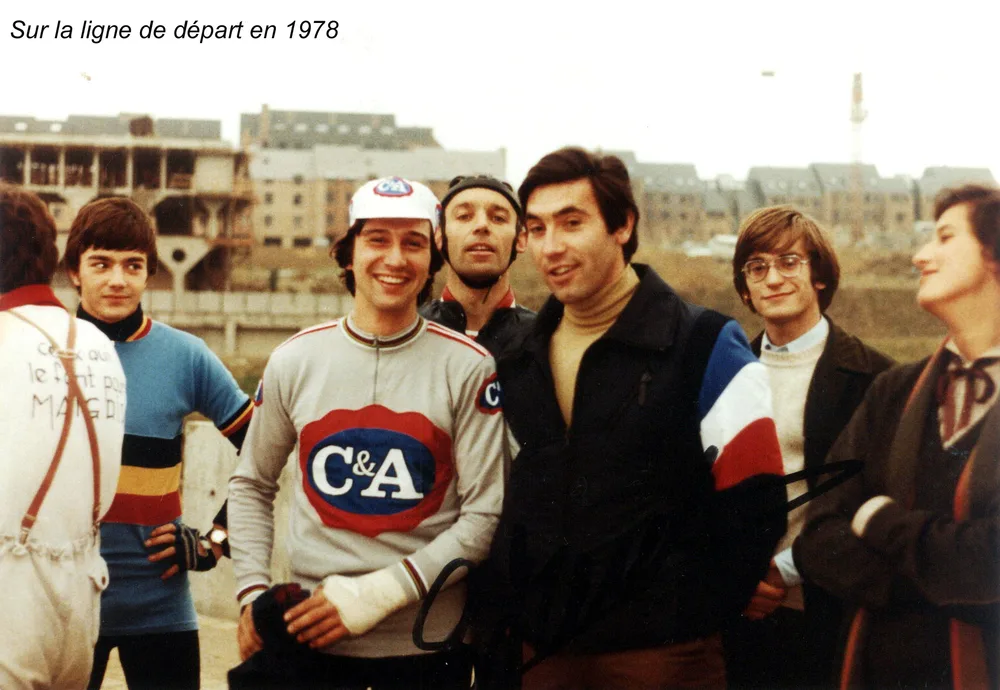 Photo de 1978 portant la mention « Sur la ligne de départ en 1978 » : Eddy Merckx parmi des coureurs et des étudiants, devant des immeubles en construction de Louvain-la-Neuve